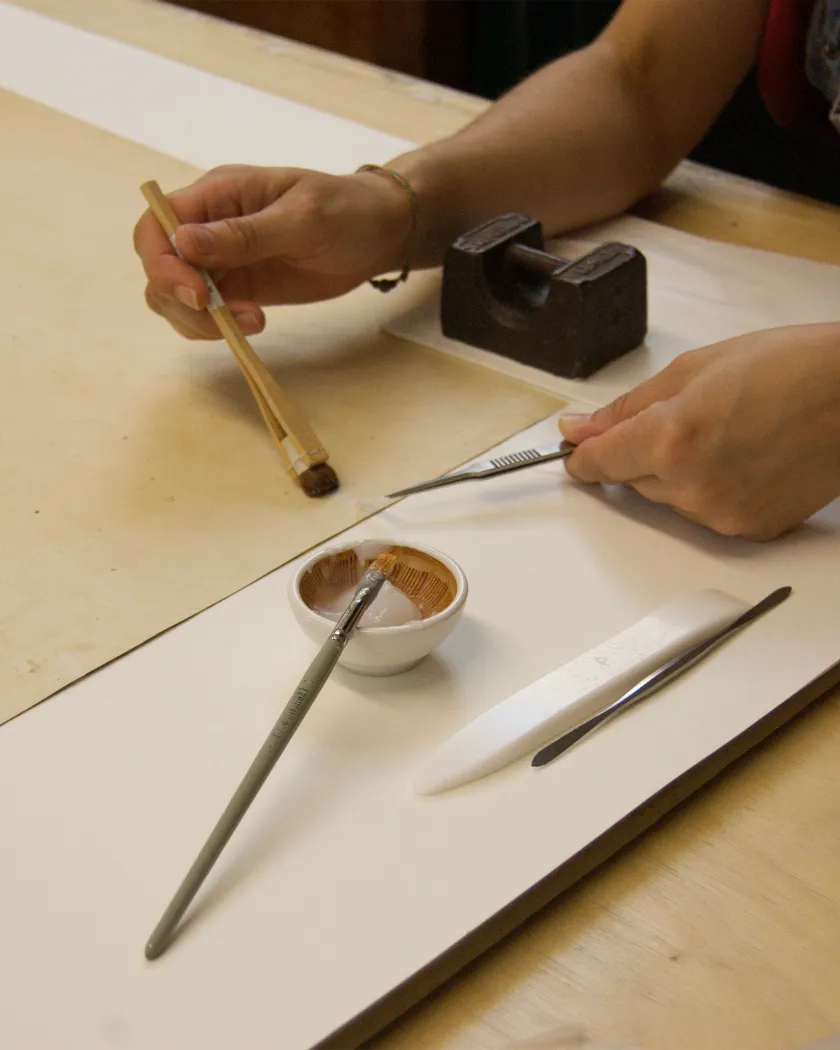 Paper conservator carrying out treatment with specialist brushes and tools